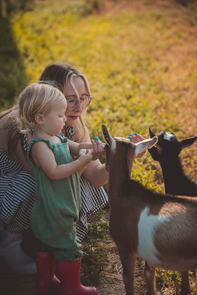 Chelsea and her child petting goats