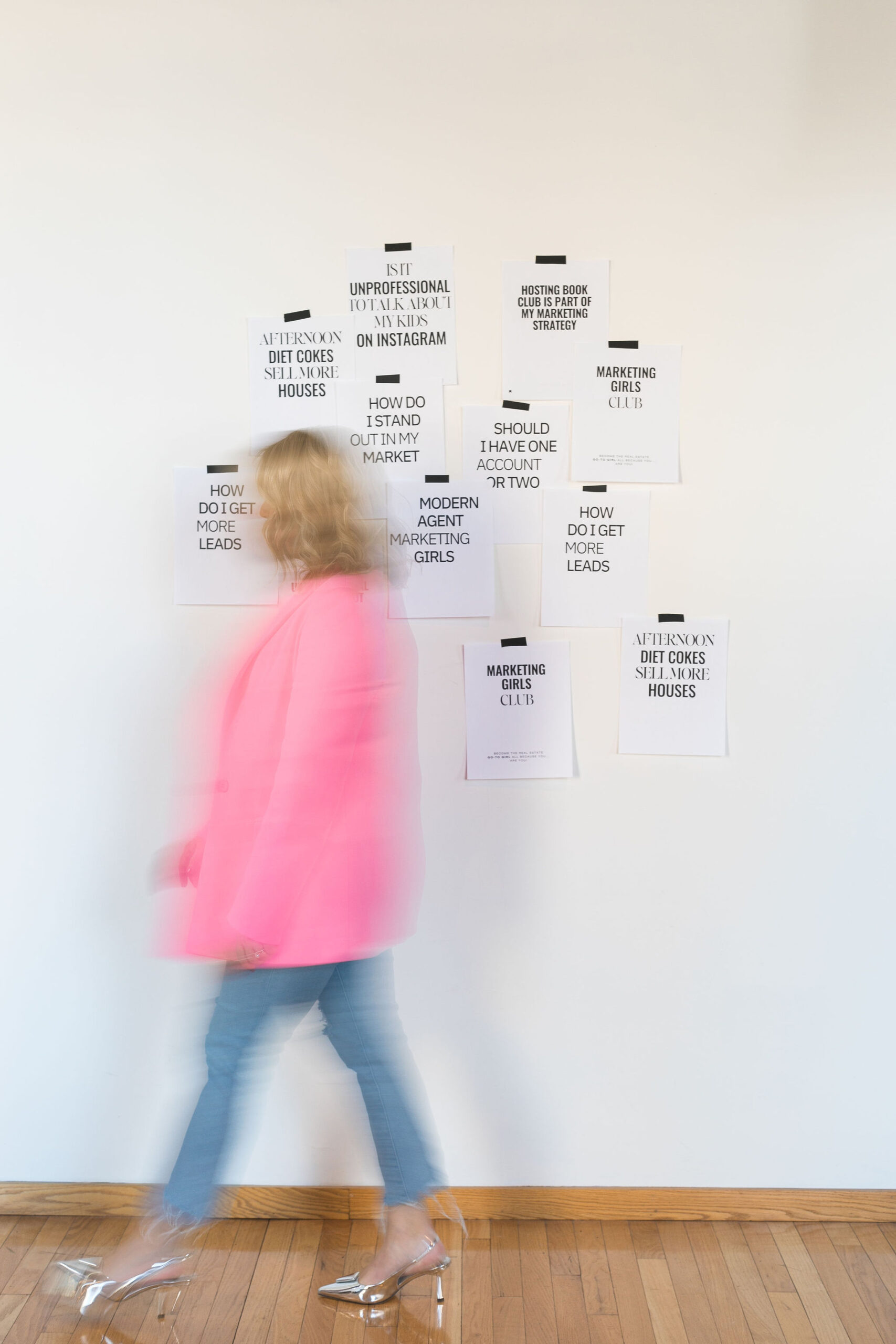 Chelsea walking in front of a wall with papers taped to it, and she looks blurry because she's moving