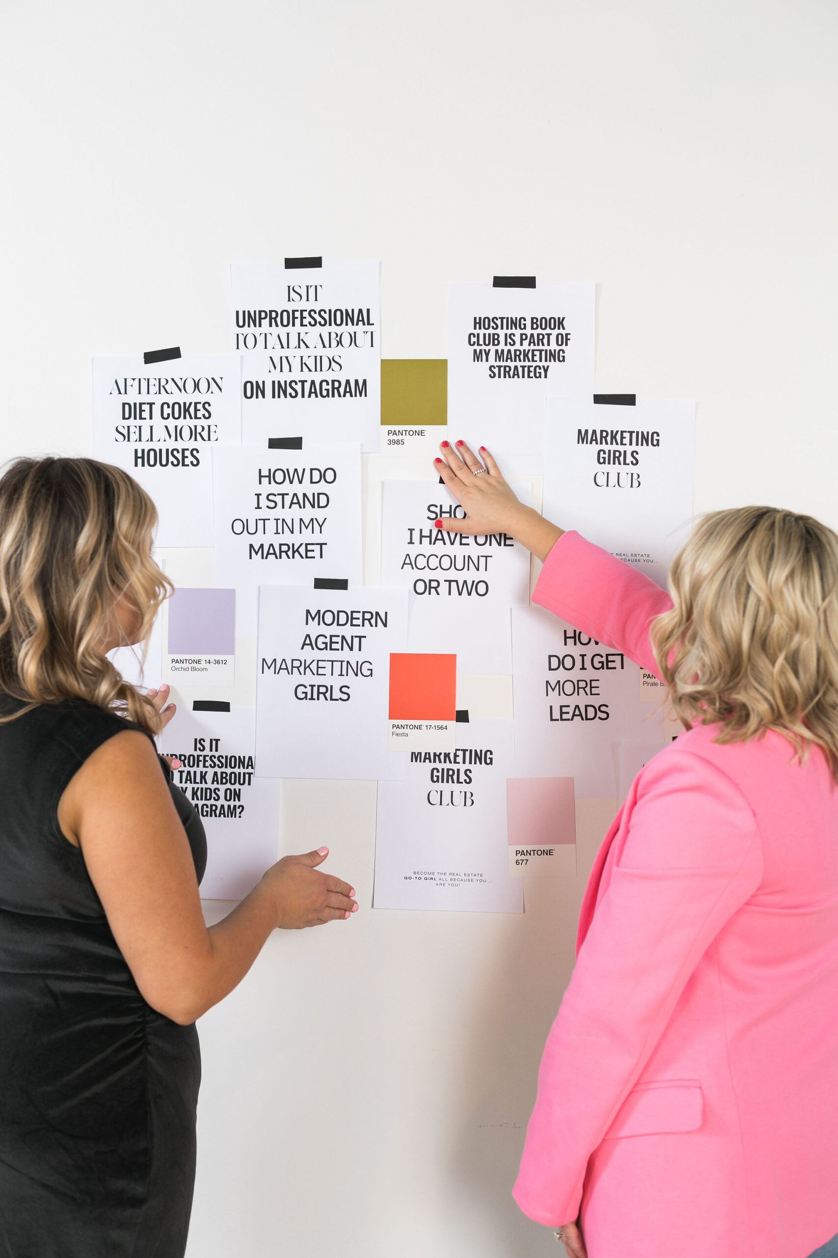Chelsea and Kayla looking at questions taped on a wall